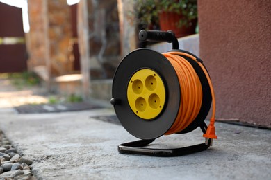 Photo of Extension cord reel on asphalt outdoors, space for text