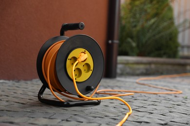 Photo of Extension cord reel on paved pathway outdoors, space for text