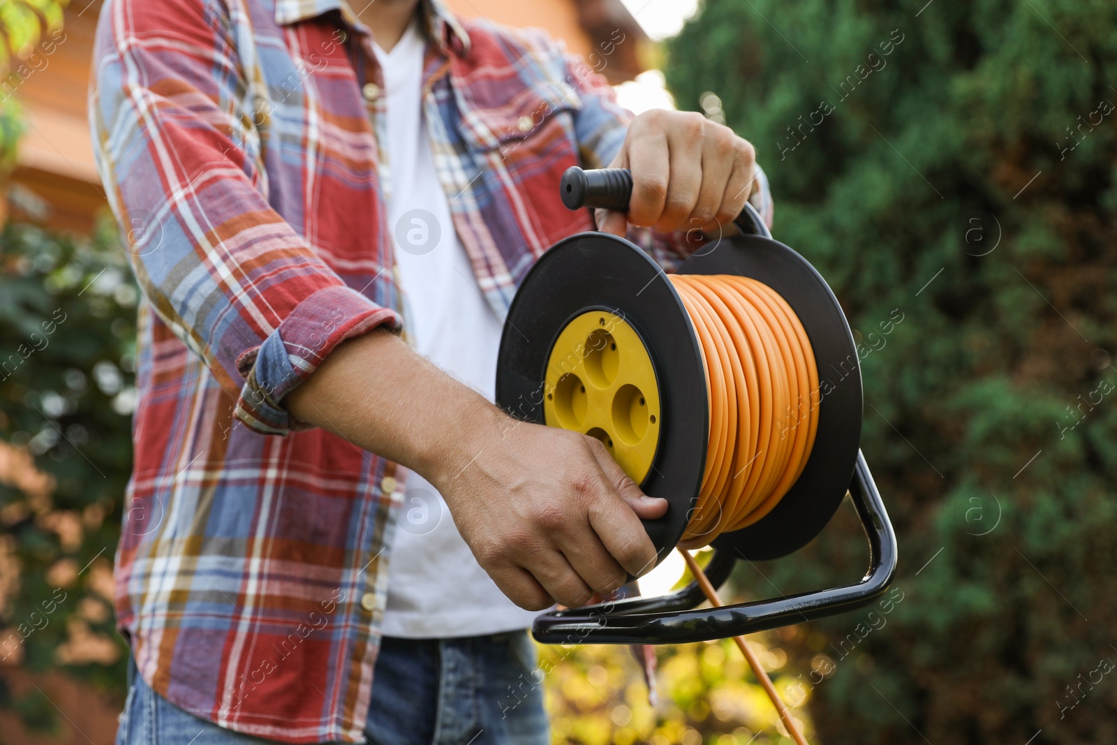 Photo of Man with extension cord reel outdoors, closeup