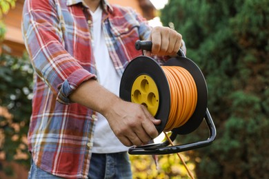 Photo of Man with extension cord reel outdoors, closeup