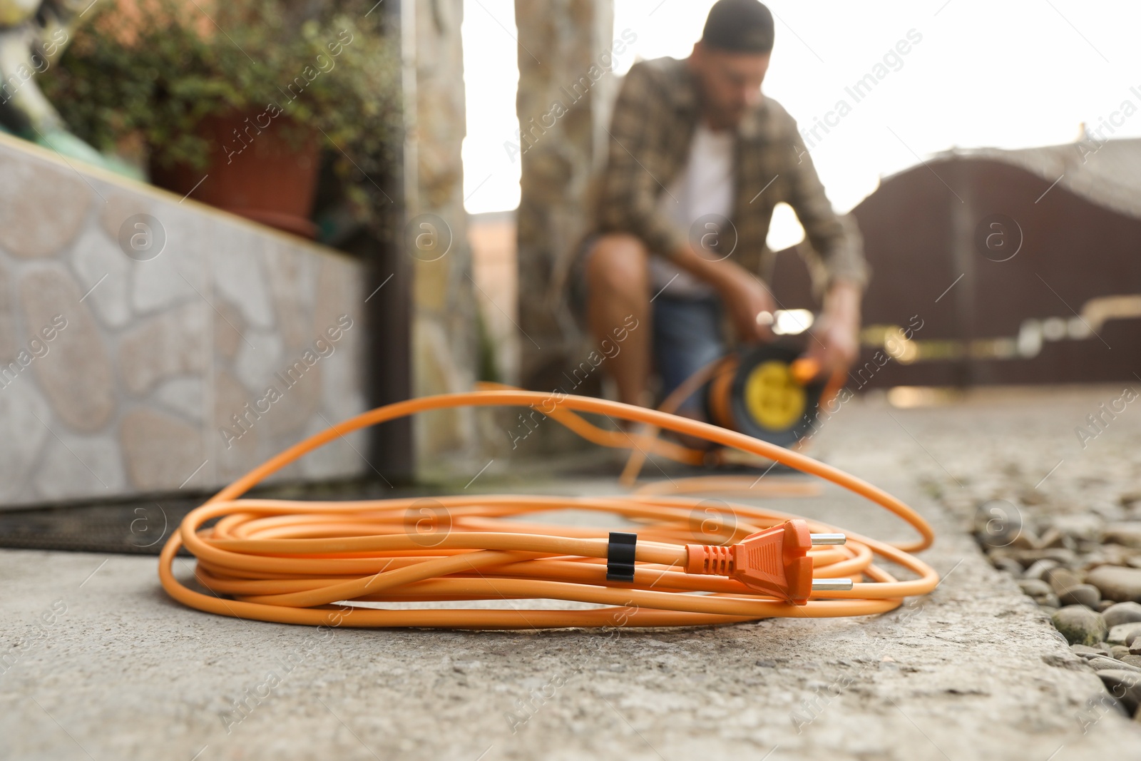 Photo of Man with extension cord reel outdoors, selective focus