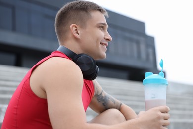 Photo of Smiling man with shaker of protein drink outdoors