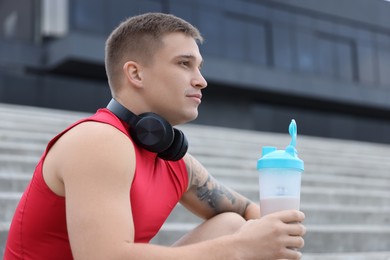 Photo of Athletic man with shaker of protein drink outdoors