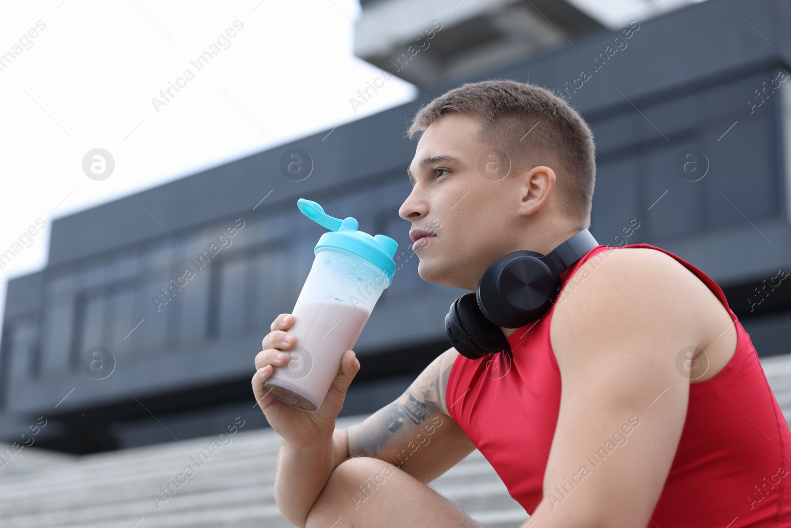 Photo of Handsome athletic man drinking protein shake outdoors