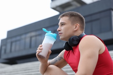 Photo of Handsome athletic man drinking protein shake outdoors