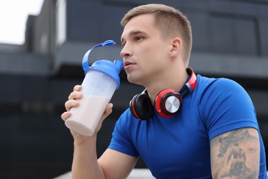 Photo of Handsome athletic man drinking protein shake outdoors