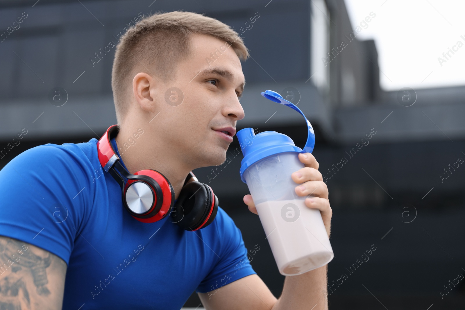 Photo of Handsome athletic man drinking protein shake outdoors