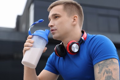 Photo of Handsome athletic man drinking protein shake outdoors