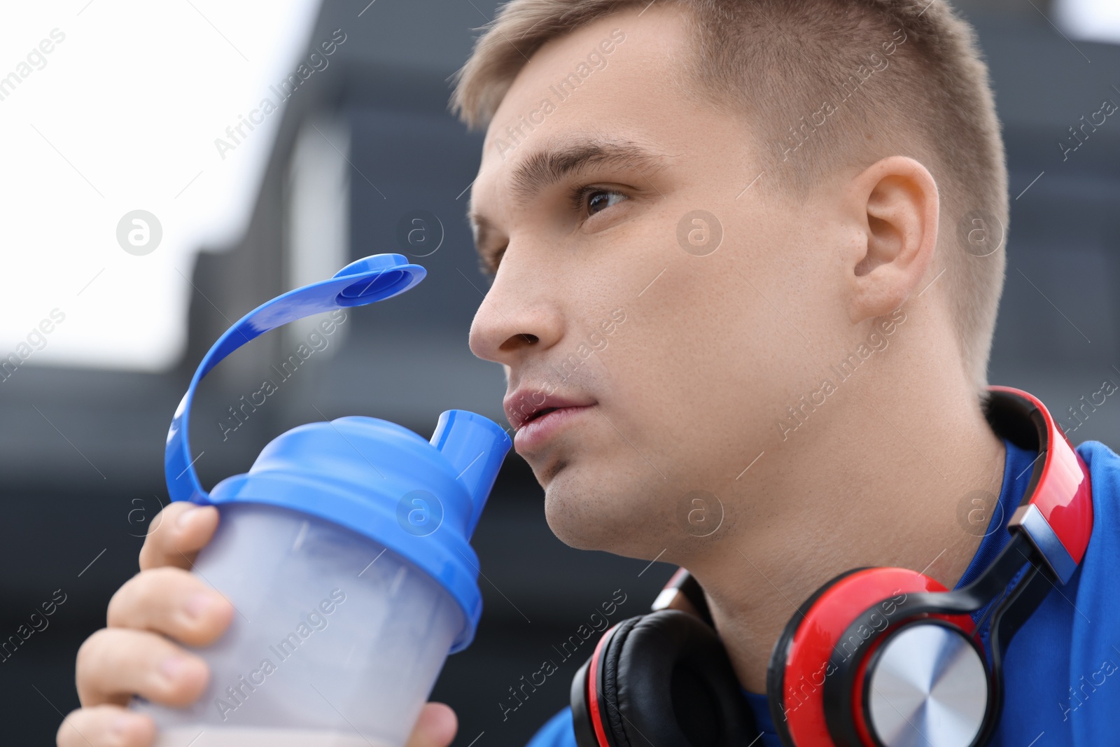 Photo of Handsome athletic man drinking protein shake outdoors