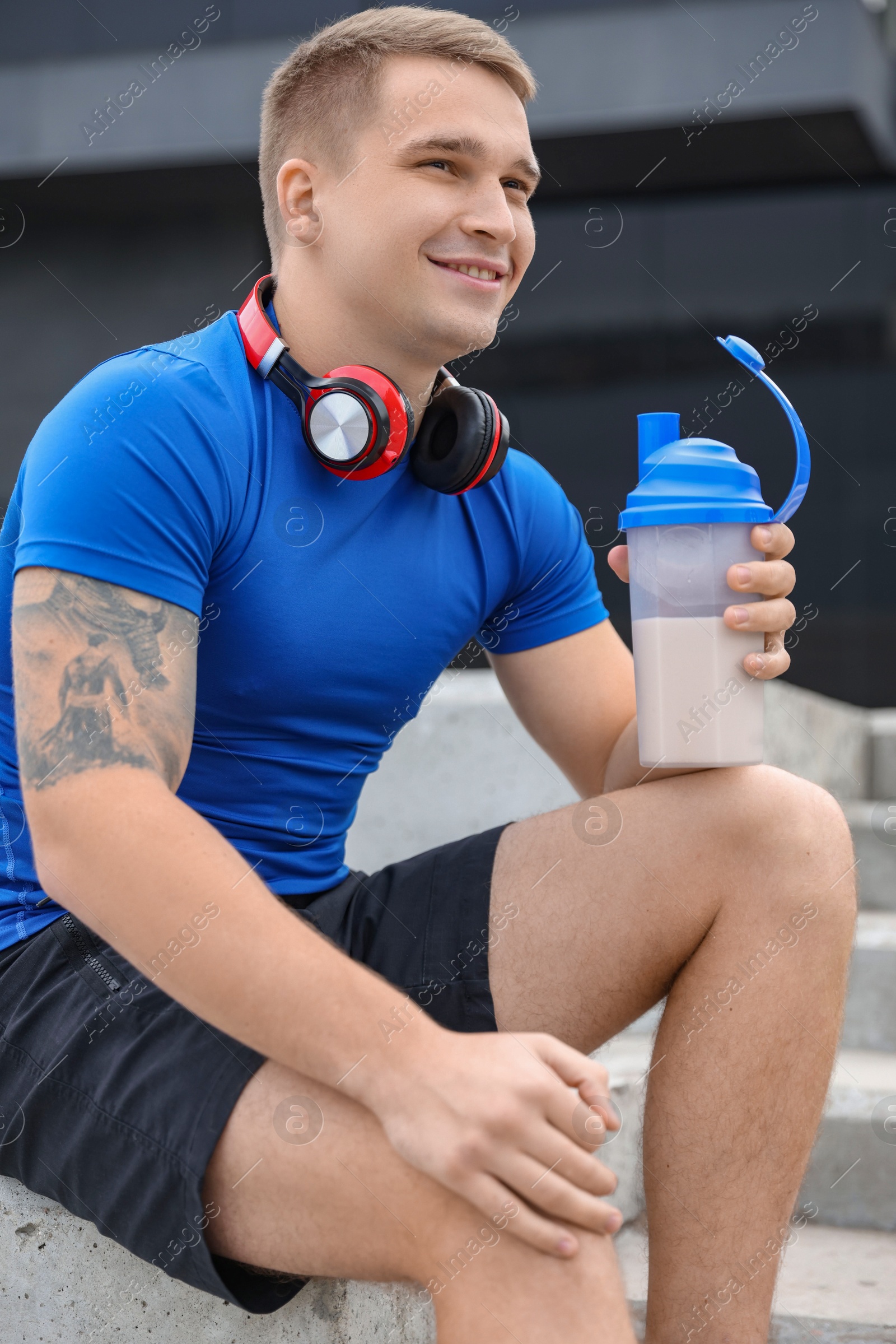 Photo of Smiling man with shaker of protein drink outdoors