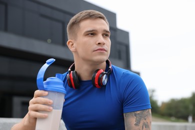 Photo of Athletic man with shaker of protein drink outdoors