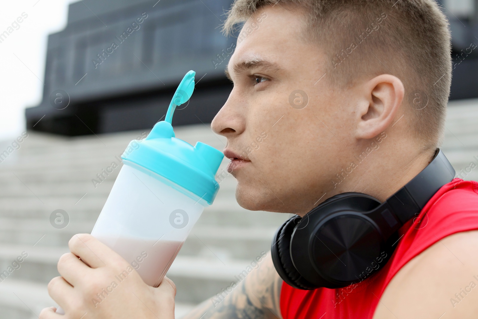 Photo of Handsome athletic man drinking protein shake outdoors