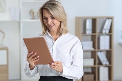 Photo of Portrait of happy businesswoman using tablet in office