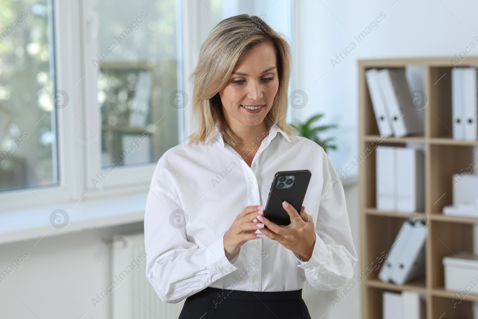 Photo of Portrait of businesswoman using smartphone in office