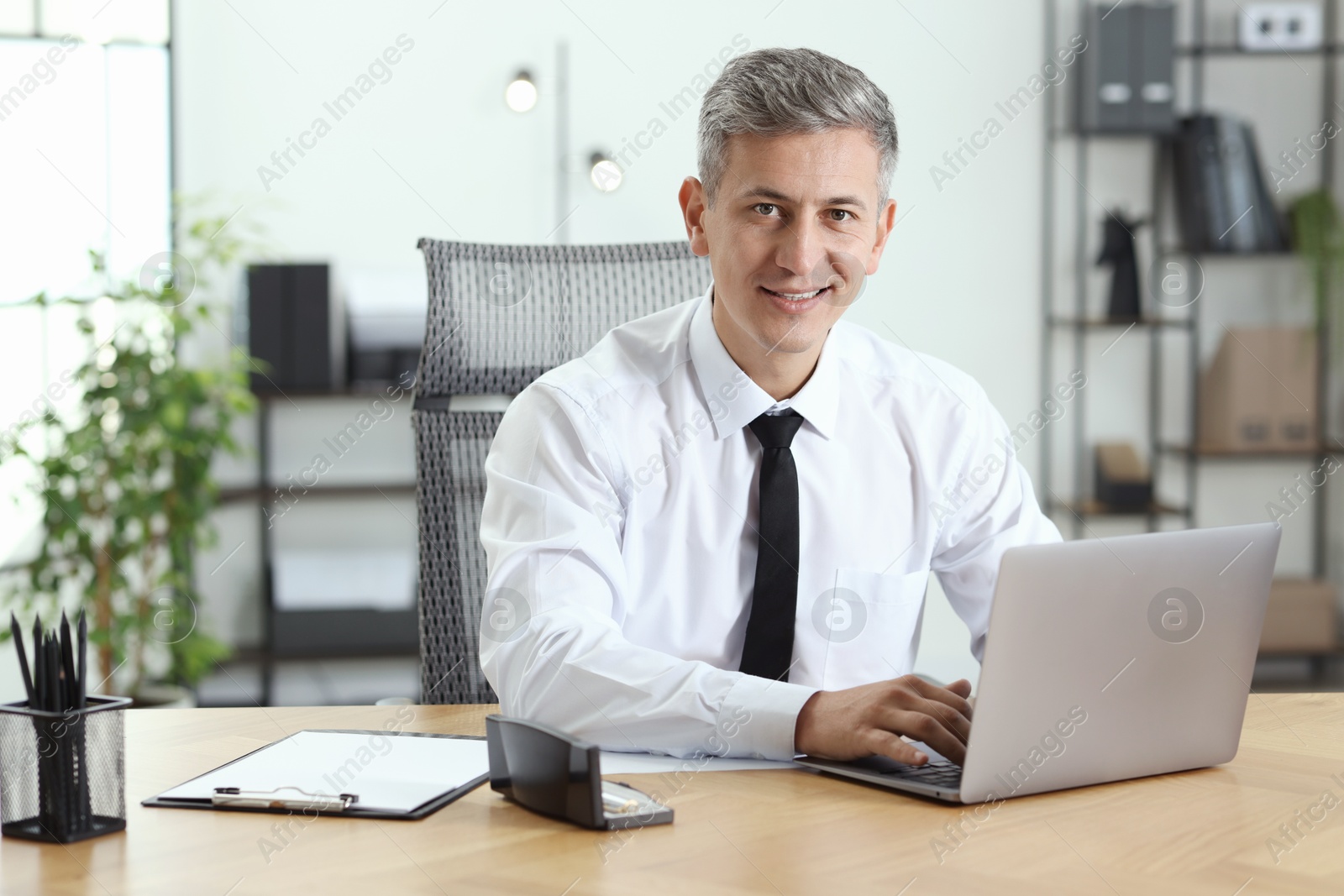 Photo of Businessman working on laptop at table in office