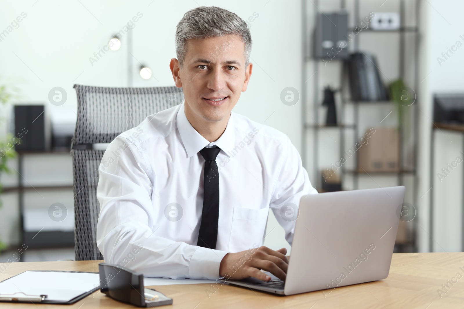 Photo of Businessman working on laptop at table in office