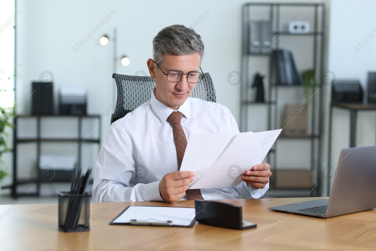 Photo of Businessman working with documents at table in office