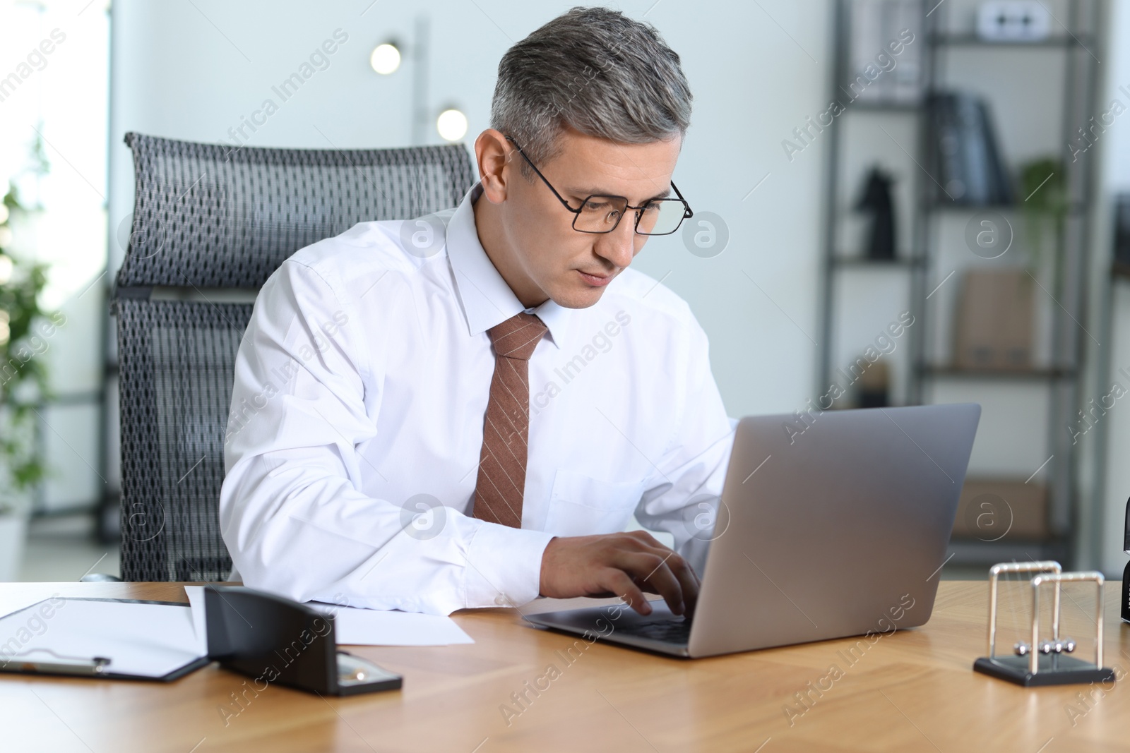 Photo of Businessman working on laptop at table in office