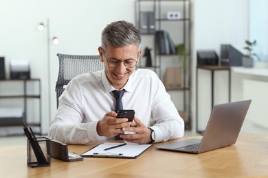 Photo of Businessman using smartphone at table in office