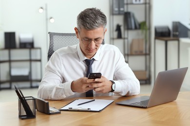 Photo of Businessman using smartphone at table in office