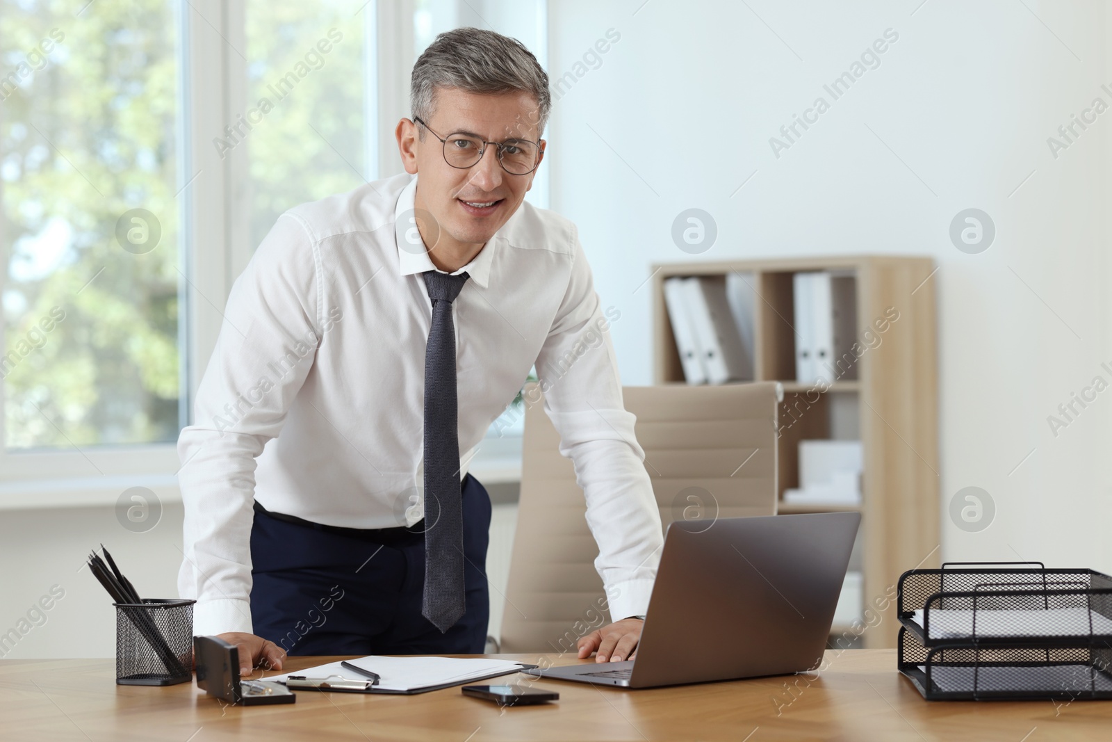 Photo of Businessman working on laptop at table in office