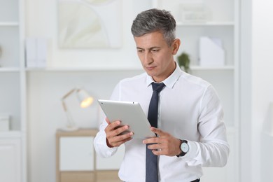 Photo of Portrait of businessman using tablet in office, space for text