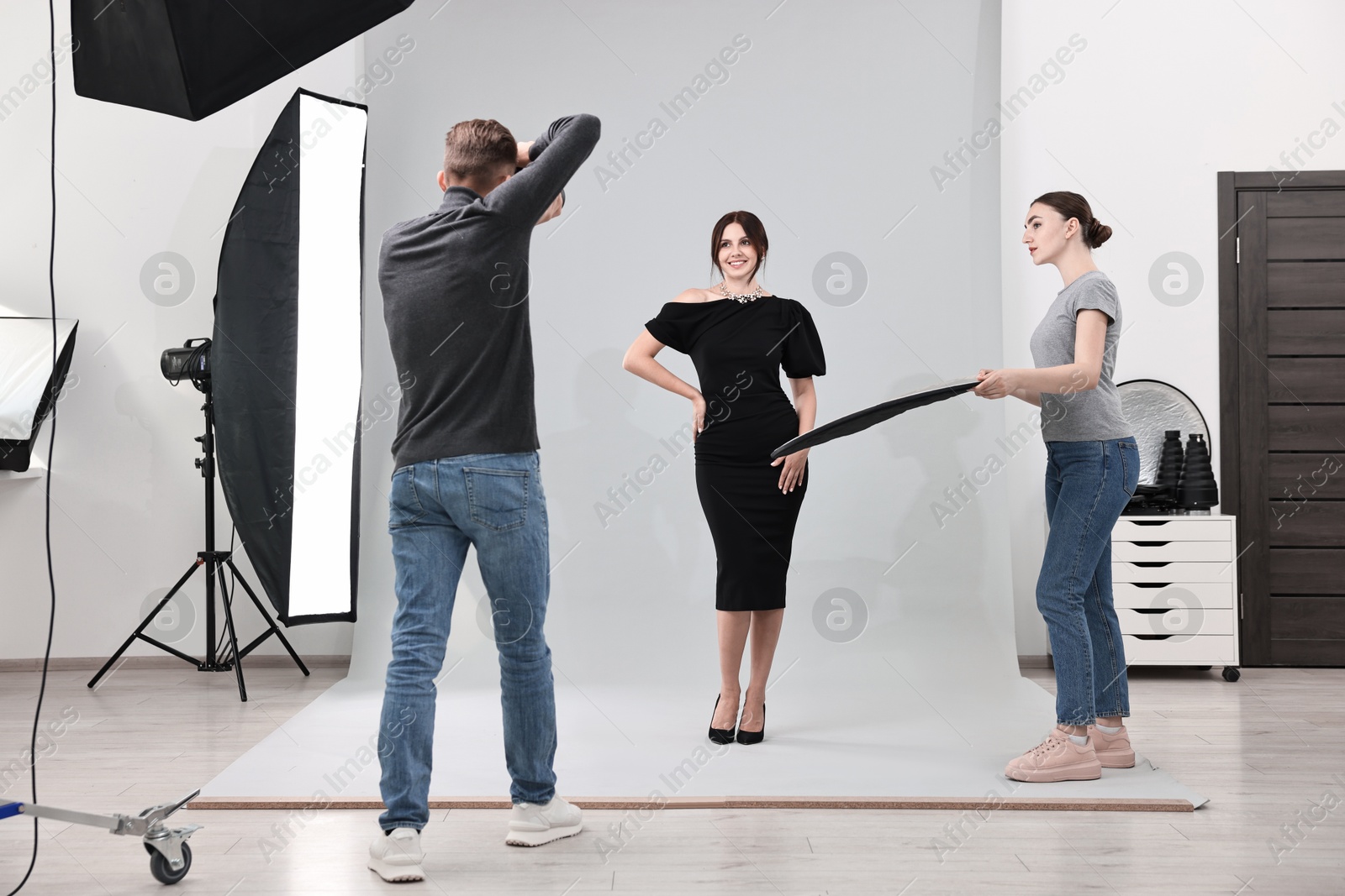 Photo of Photographer and assistant working with model in professional photo studio