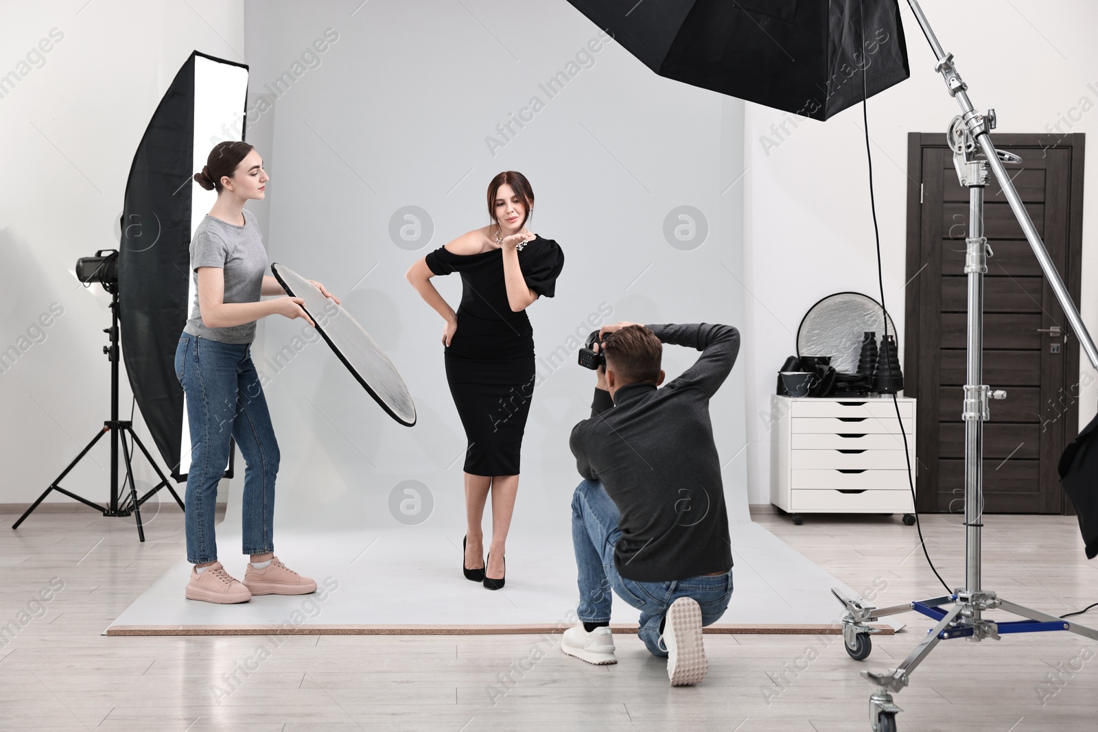 Photo of Photographer and assistant working with model in professional photo studio