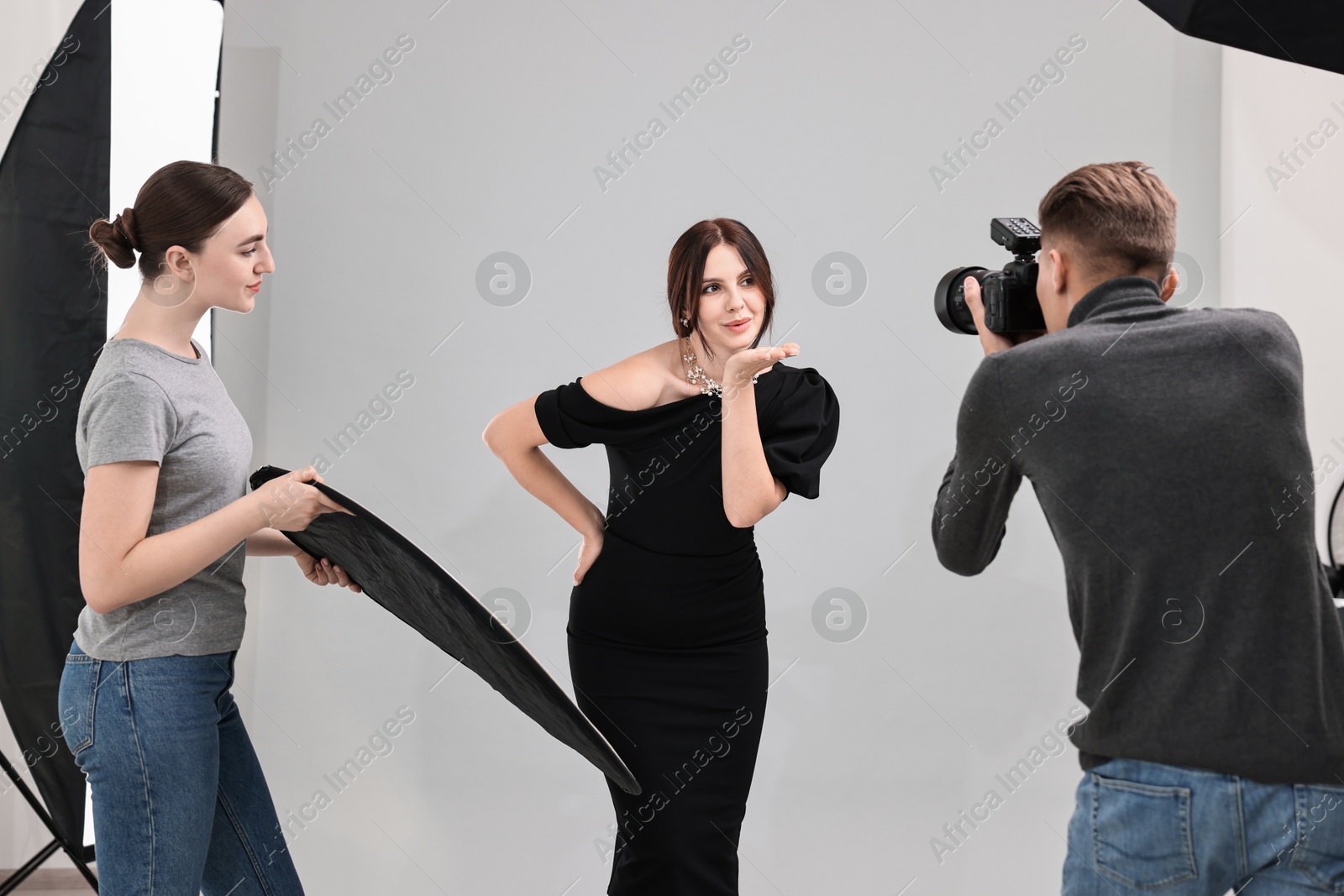 Photo of Photographer and assistant working with model in professional photo studio