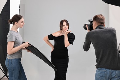 Photo of Photographer and assistant working with model in professional photo studio