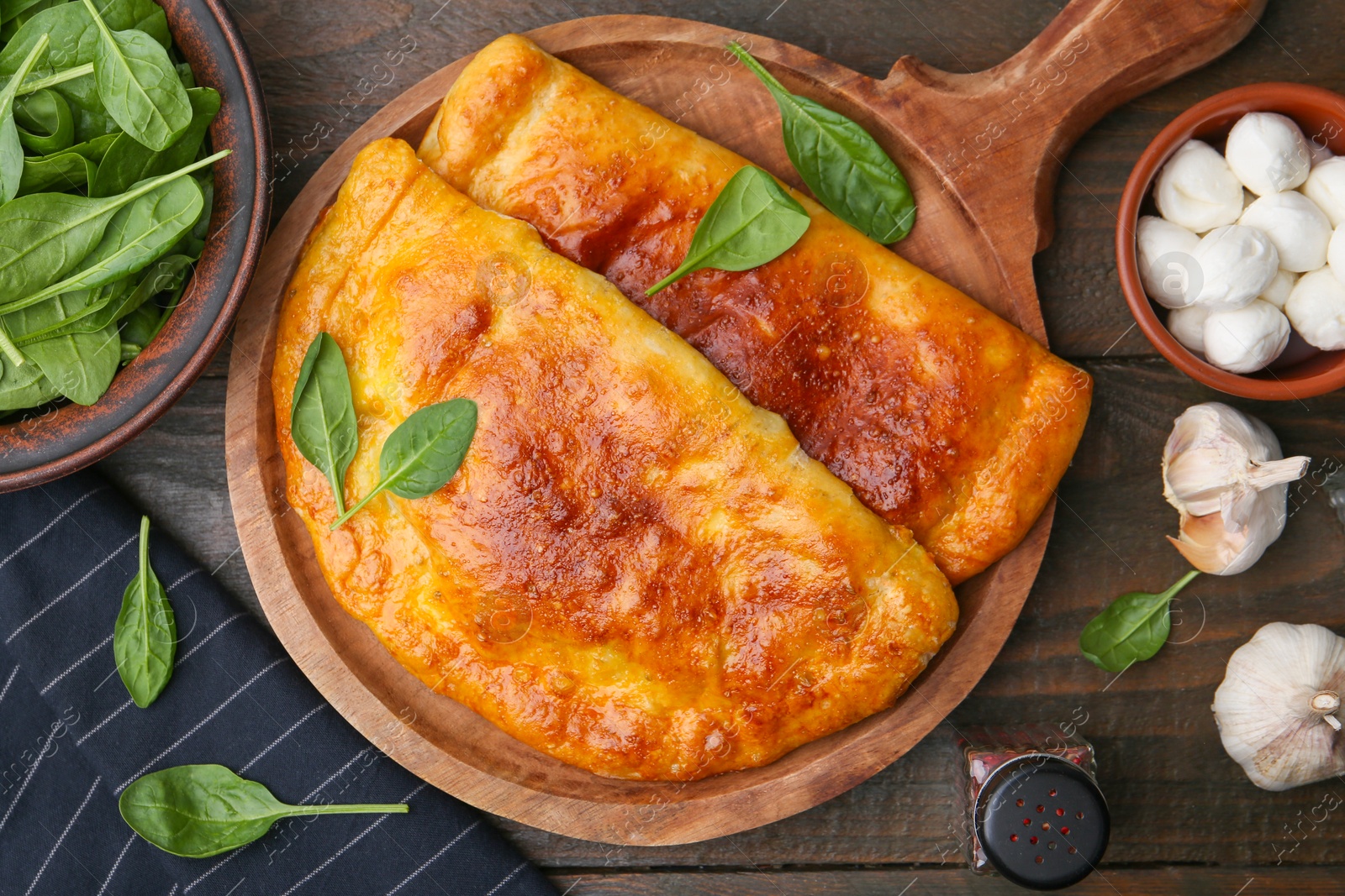 Photo of Tasty calzones with basil, mozzarella cheese and garlic on wooden table, flat lay