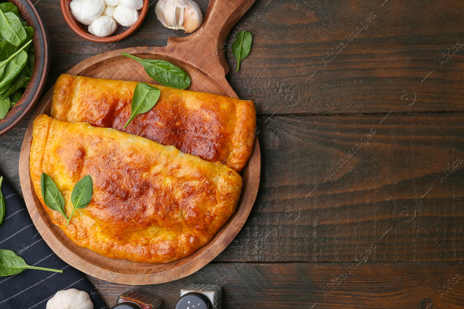 Photo of Tasty calzones with basil, mozzarella cheese and garlic on wooden table, flat lay. Space for text