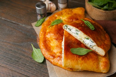 Photo of Tasty calzones with cheese and basil on wooden table, closeup. Space for text