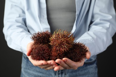 Woman holding fresh rambutans against black background, closeup