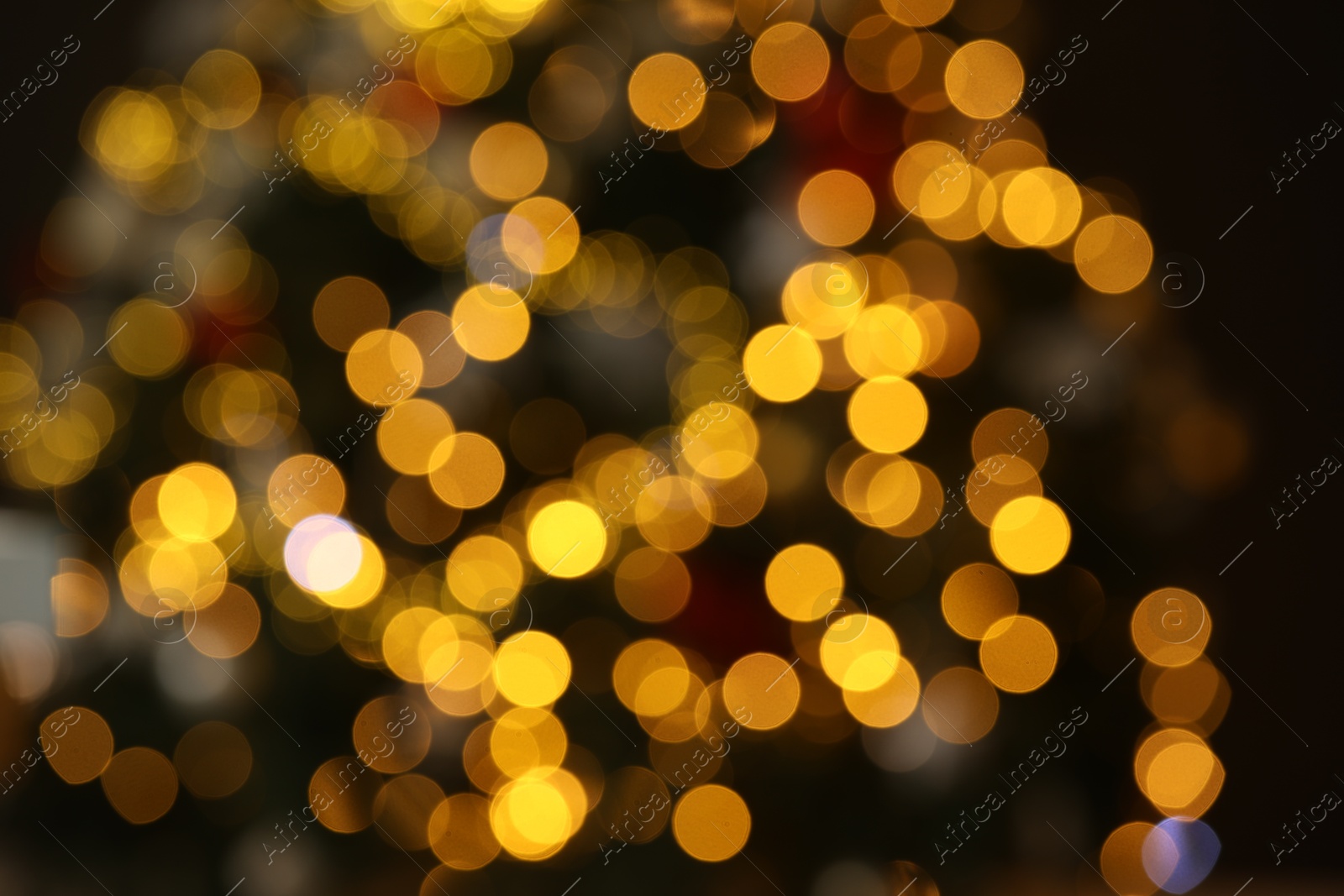 Photo of Beautiful golden lights on blurred background, bokeh effect