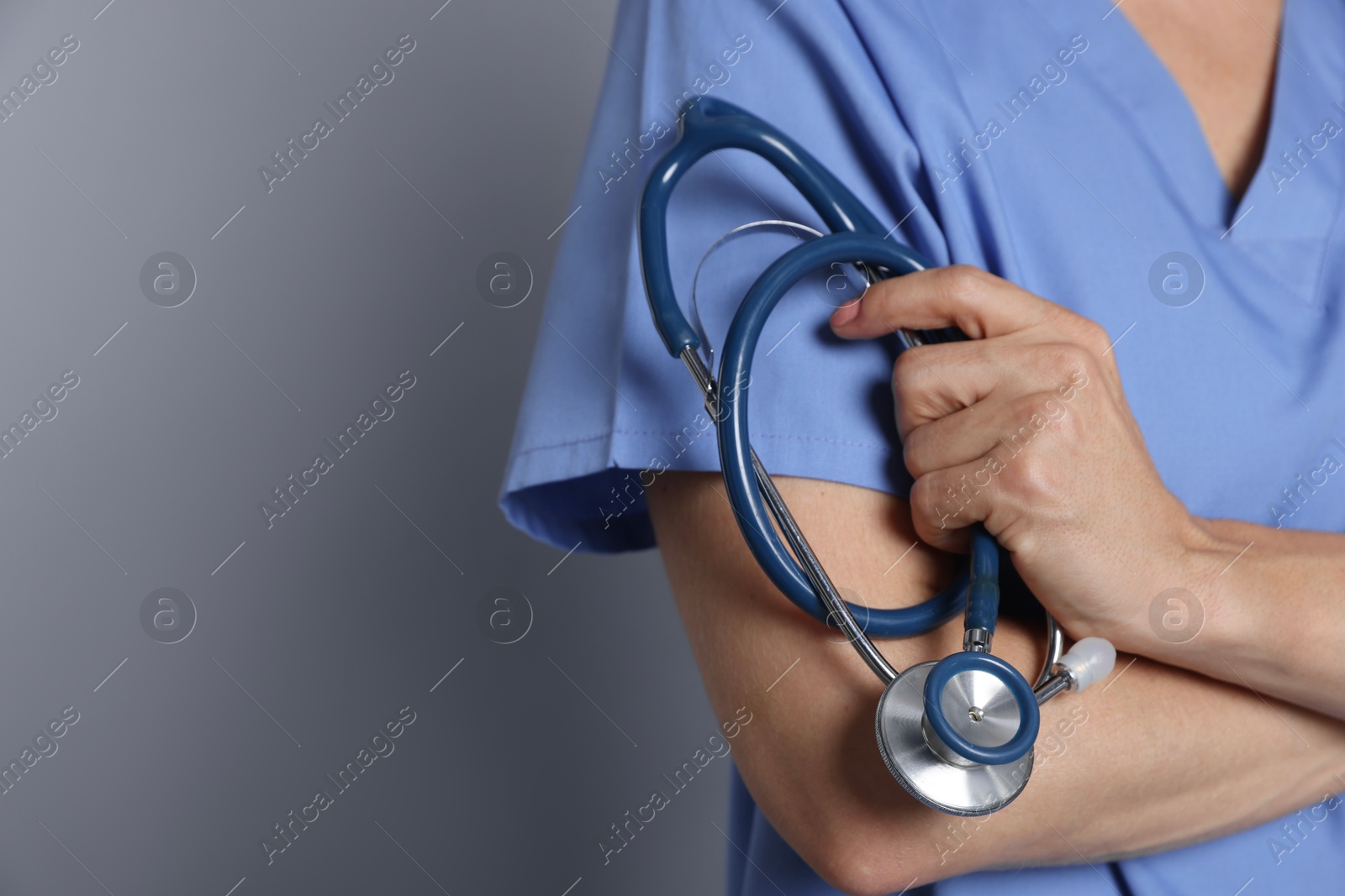 Photo of Doctor with stethoscope on gray background, closeup. Space for text