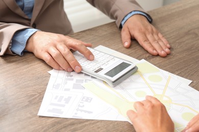 Photo of Real estate agent working with client at wooden table, closeup