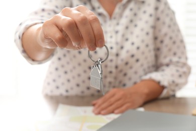 Photo of Real estate agent with house key at table, closeup