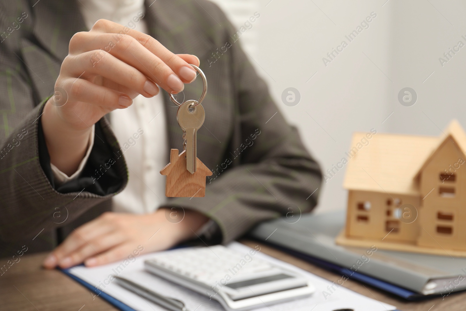 Photo of Real estate agent with house key at table, closeup