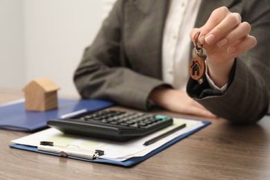 Real estate agent with house key and stationery at wooden table, closeup