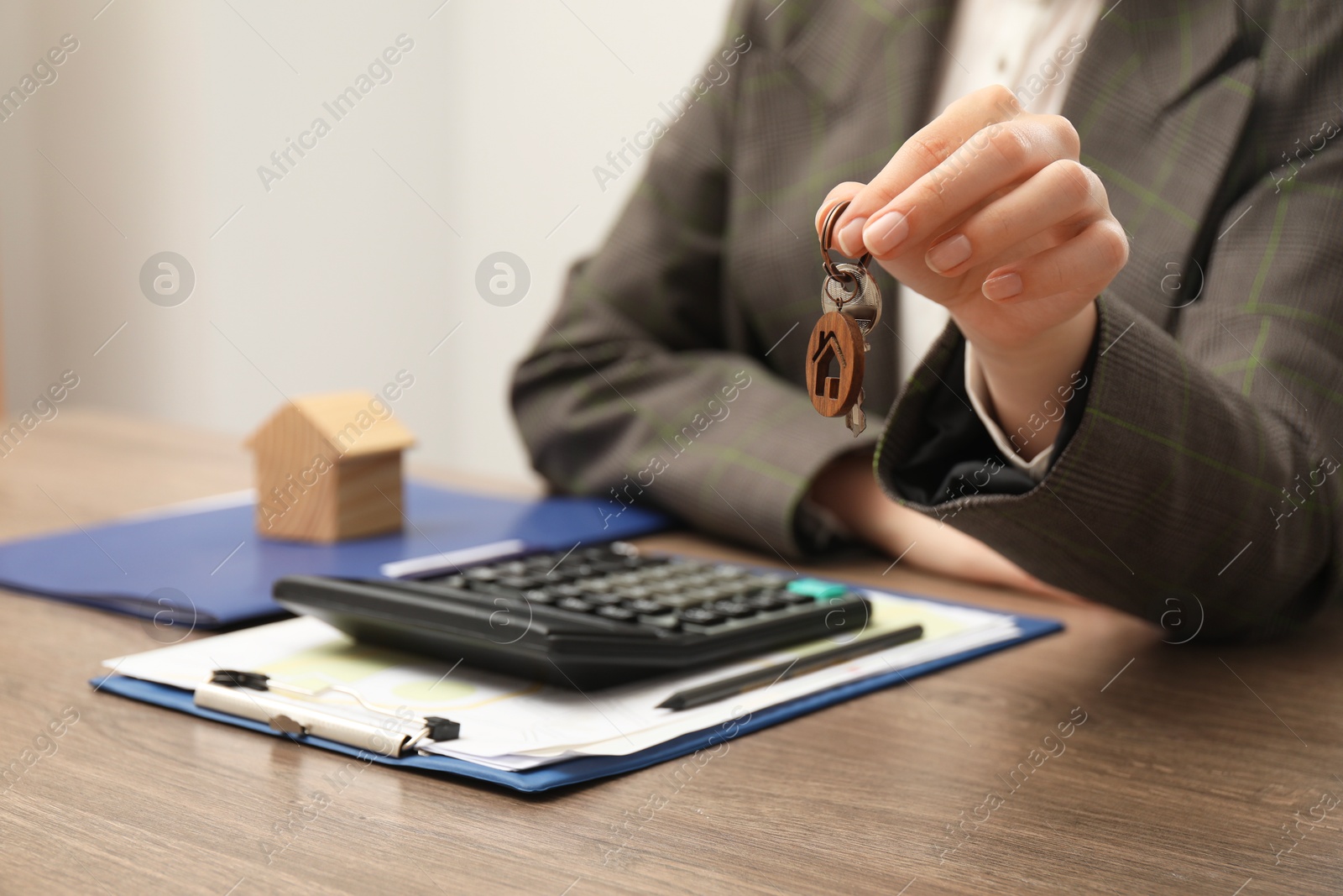 Photo of Real estate agent with house key and stationery at wooden table, closeup