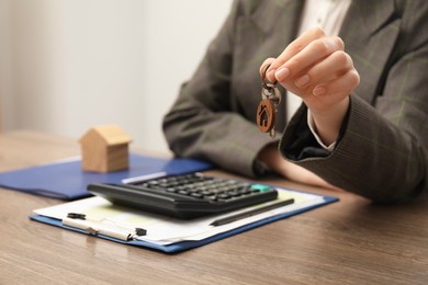 Real estate agent with house key and stationery at wooden table, closeup