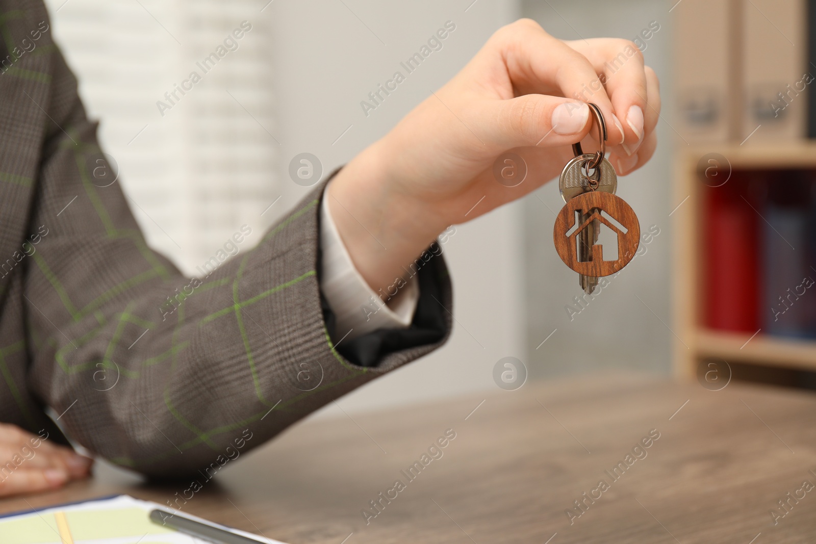 Photo of Real estate agent with house key at table, closeup