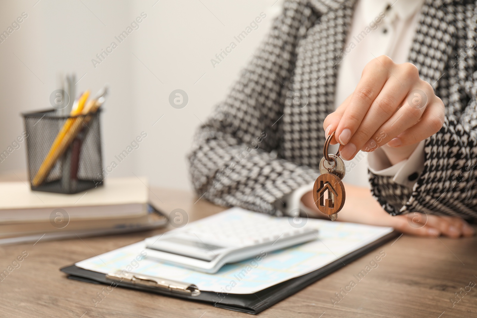 Photo of Real estate agent with house key at wooden table, closeup