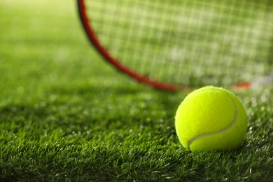 Photo of Tennis racket and ball on green artificial grass, selective focus