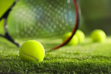 Photo of Tennis racket and ball on green artificial grass, selective focus