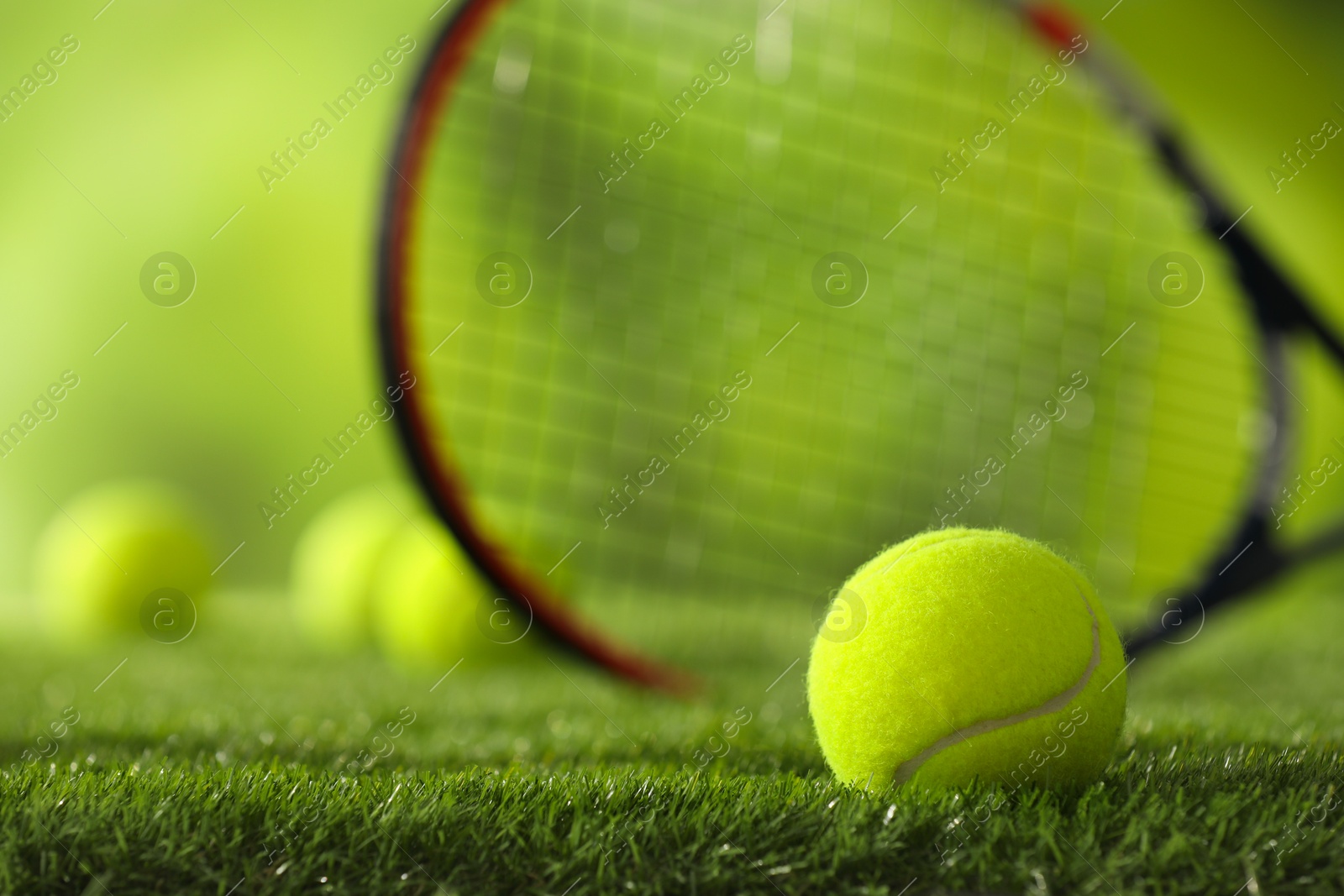 Photo of Tennis racket and ball on green artificial grass, selective focus