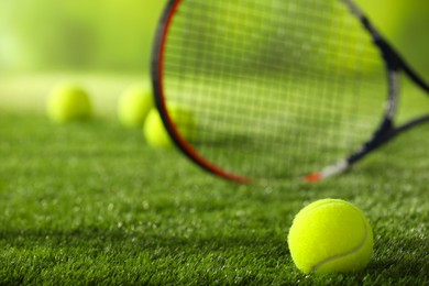 Photo of Tennis racket and ball on green artificial grass, selective focus