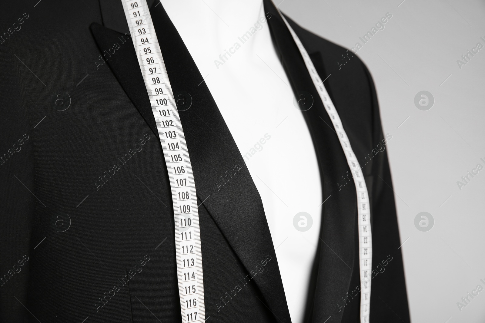 Photo of Male mannequin with elegant suit jacket and measuring tape on grey background, closeup