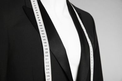 Photo of Male mannequin with elegant suit jacket and measuring tape on grey background, closeup